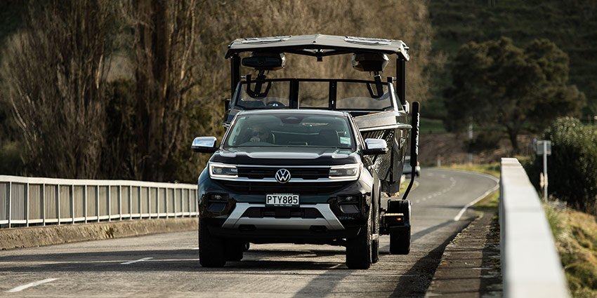 A ute driving over a bridge towing a boat