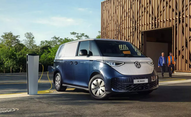 Blue and white electric van parked with a charger