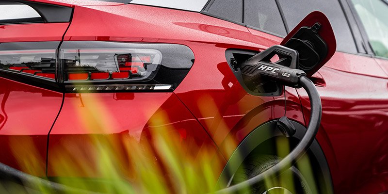 Charging cable plugged into the side of a red electric SUV