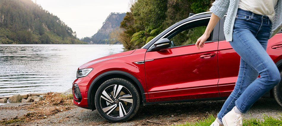 A woman running past a red Volkswagen SUV