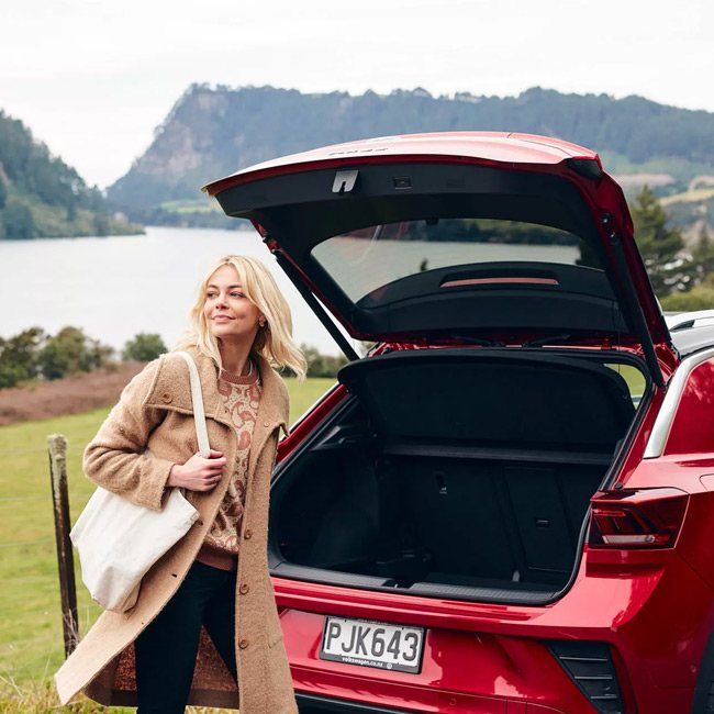A woman standing behind a red T-Roc SUV