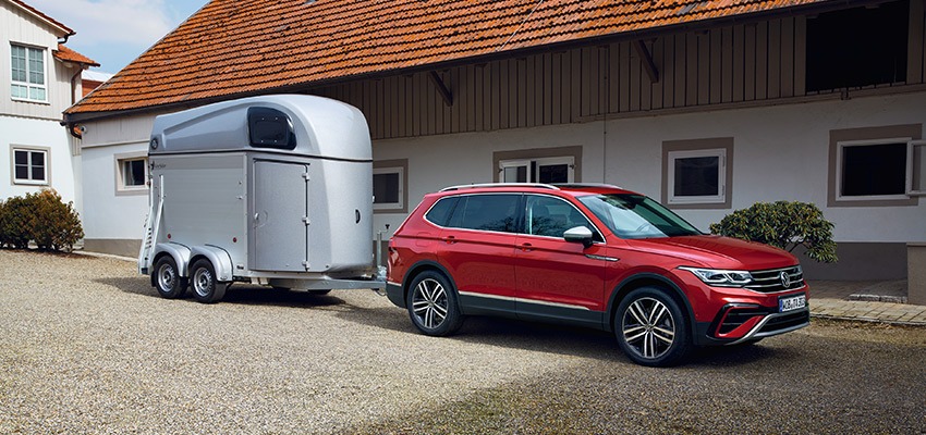 A red SUV towing a horse box