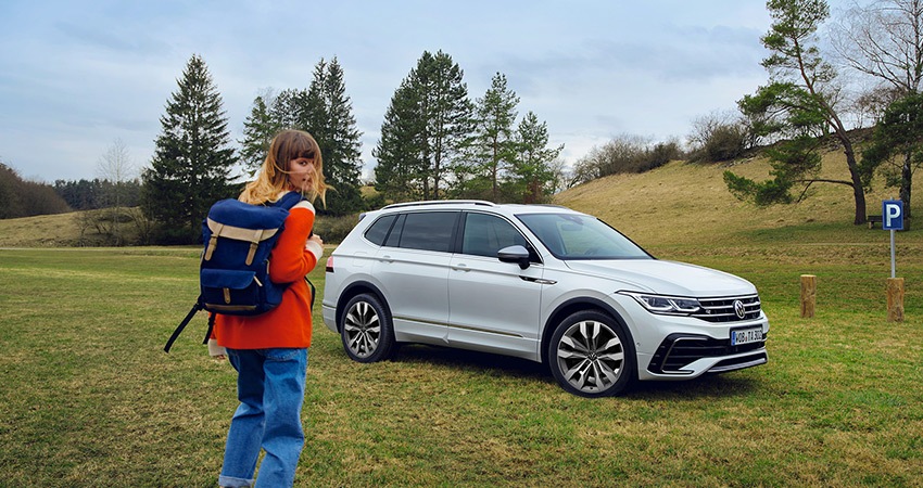 A woman walks towards a white SUV